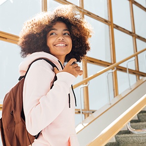 Teen with backpack smiling while walking on campus