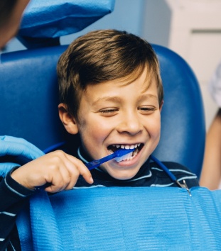 Young boy in dental chair practicing tooth brushing