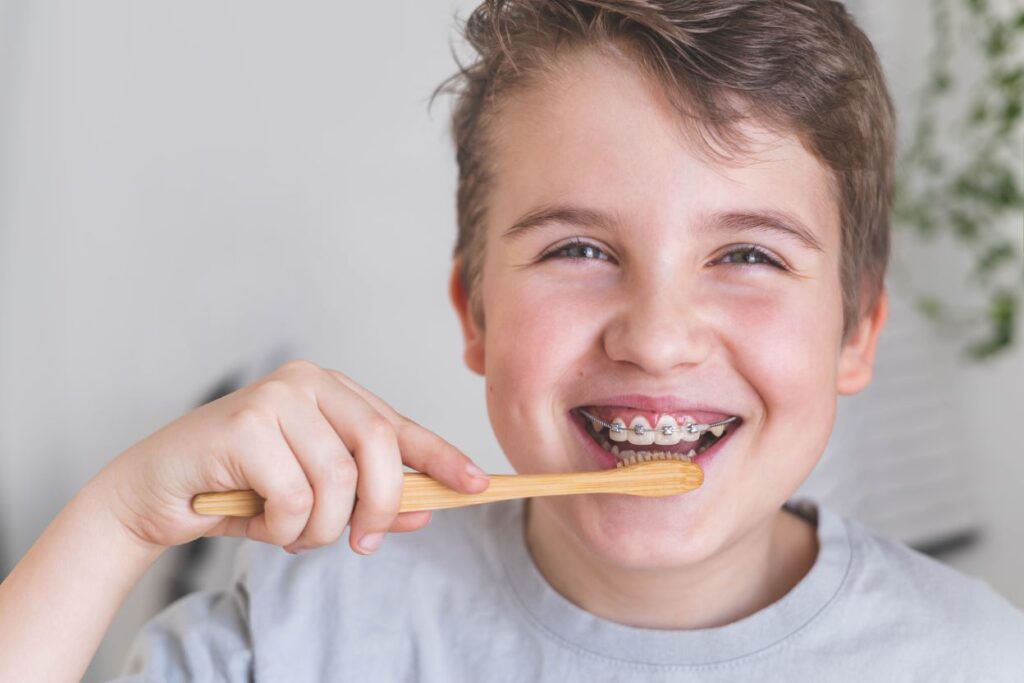 A boy with braces brushing his teeth.